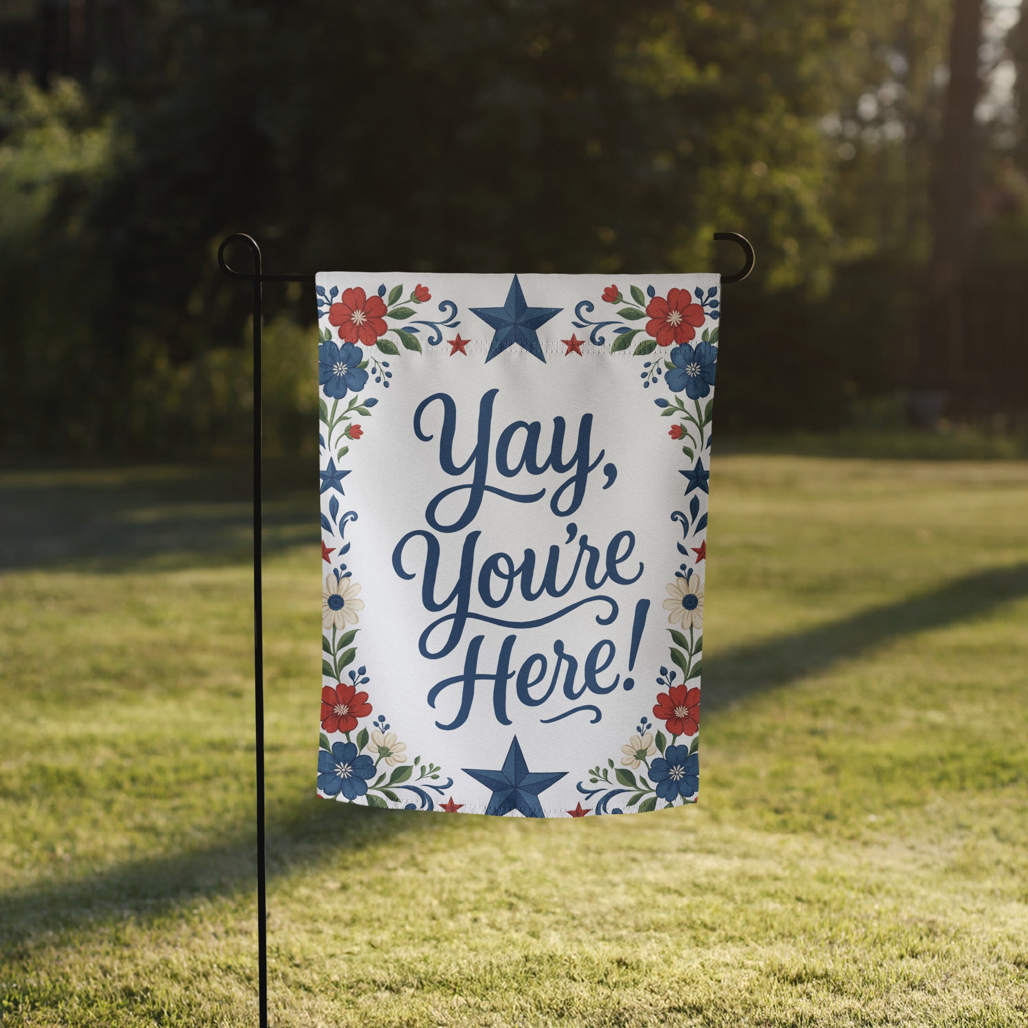 Red, white, and blue floral garden flag with folk-inspired stars and the phrase Yay, You’re Here in navy script.